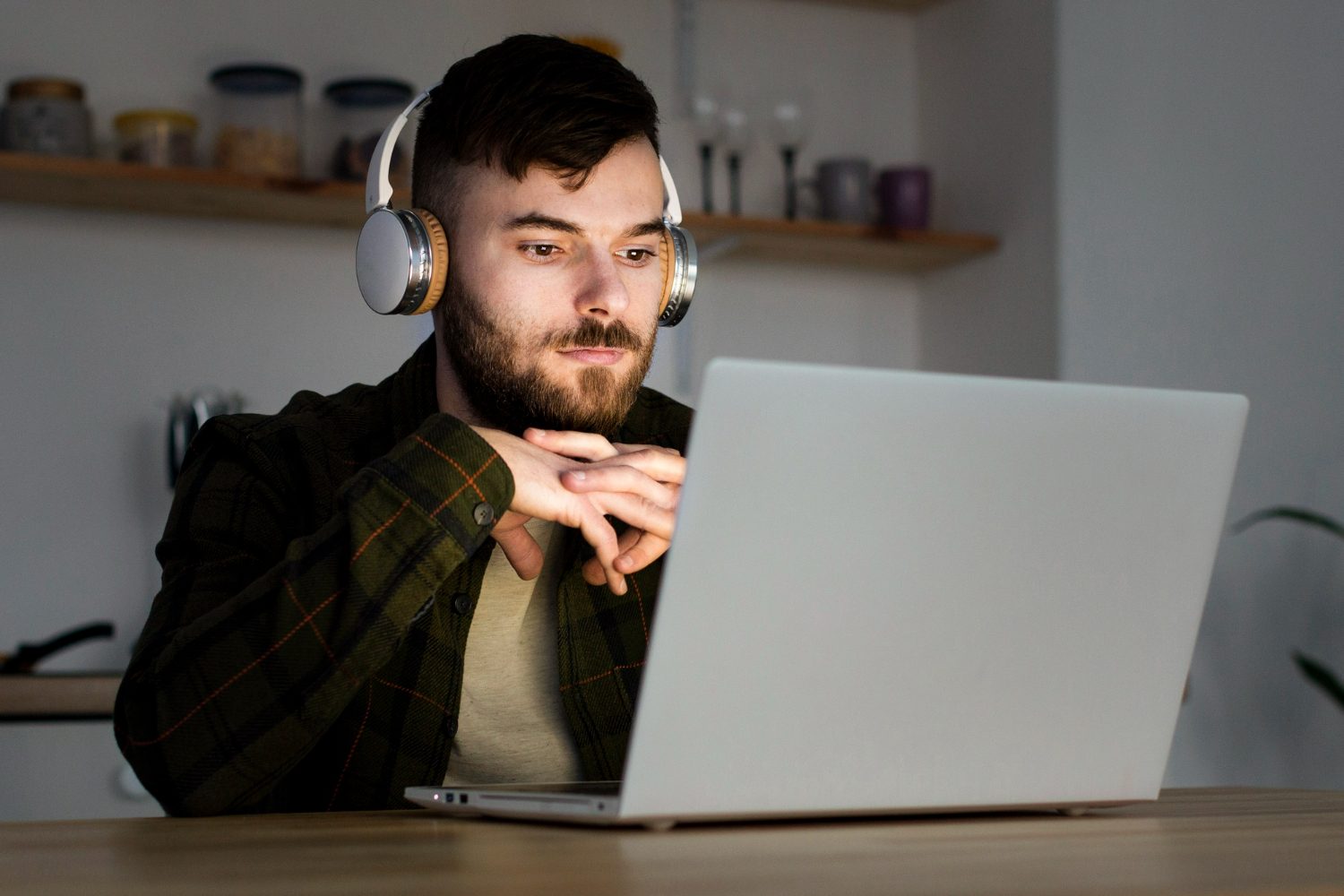 Man with headphones looking at a laptop at a desk