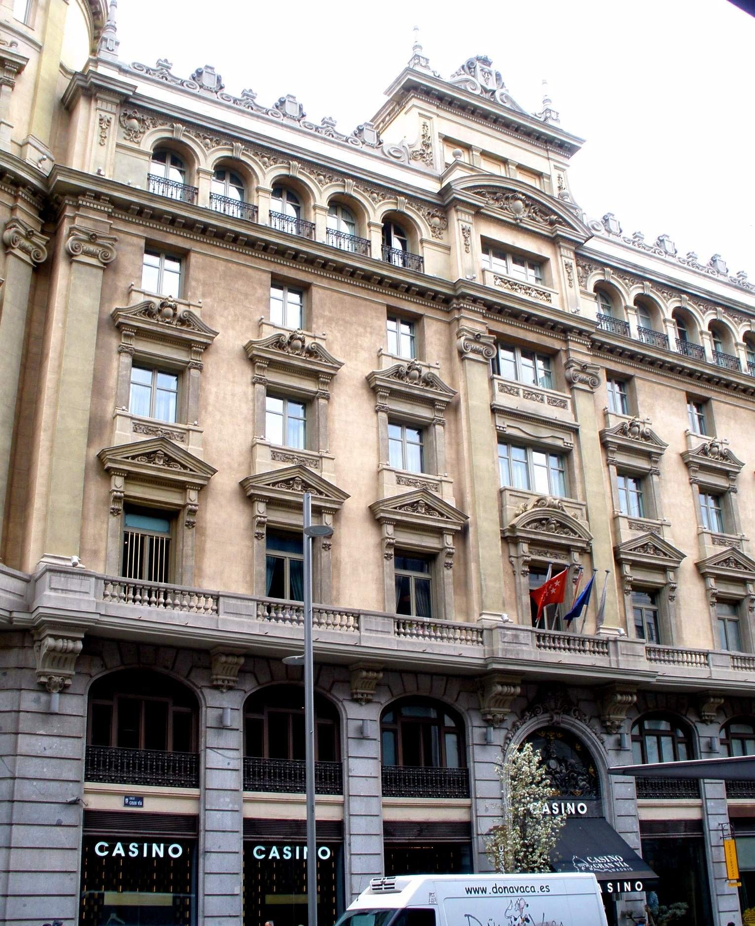 Fachada de esquina del edificio del Casino Gran Vía en Madrid, con carteles de «Casino» en la planta baja y banderas sobre el balcón