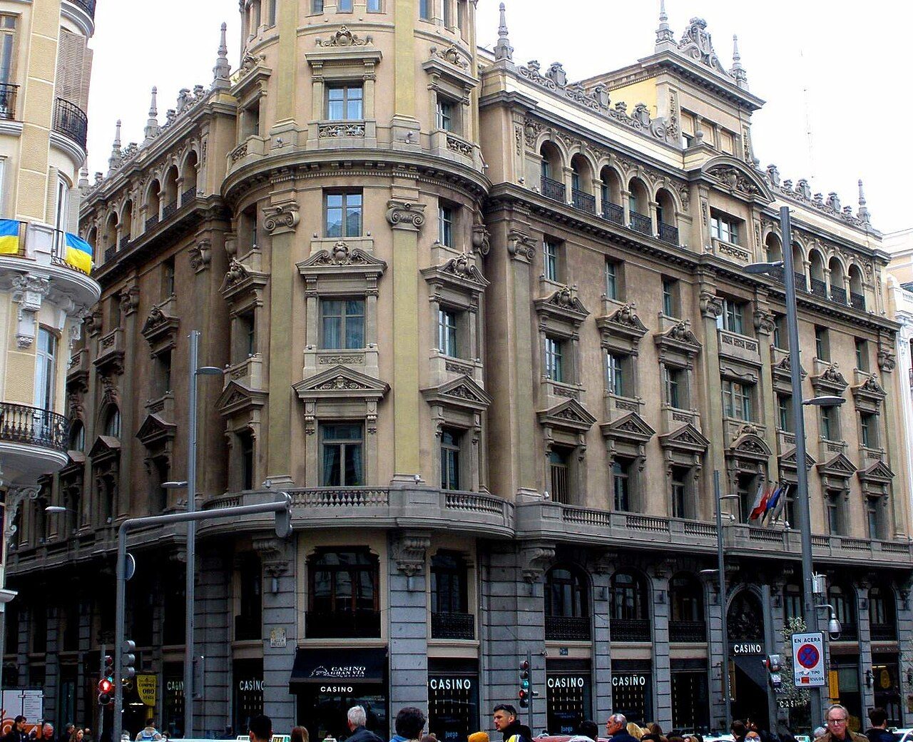 Edificio del Casino Gran Vía, en el número 24 de la Gran Vía de Madrid, con carteles de casino en la planta baja y gente en la acera