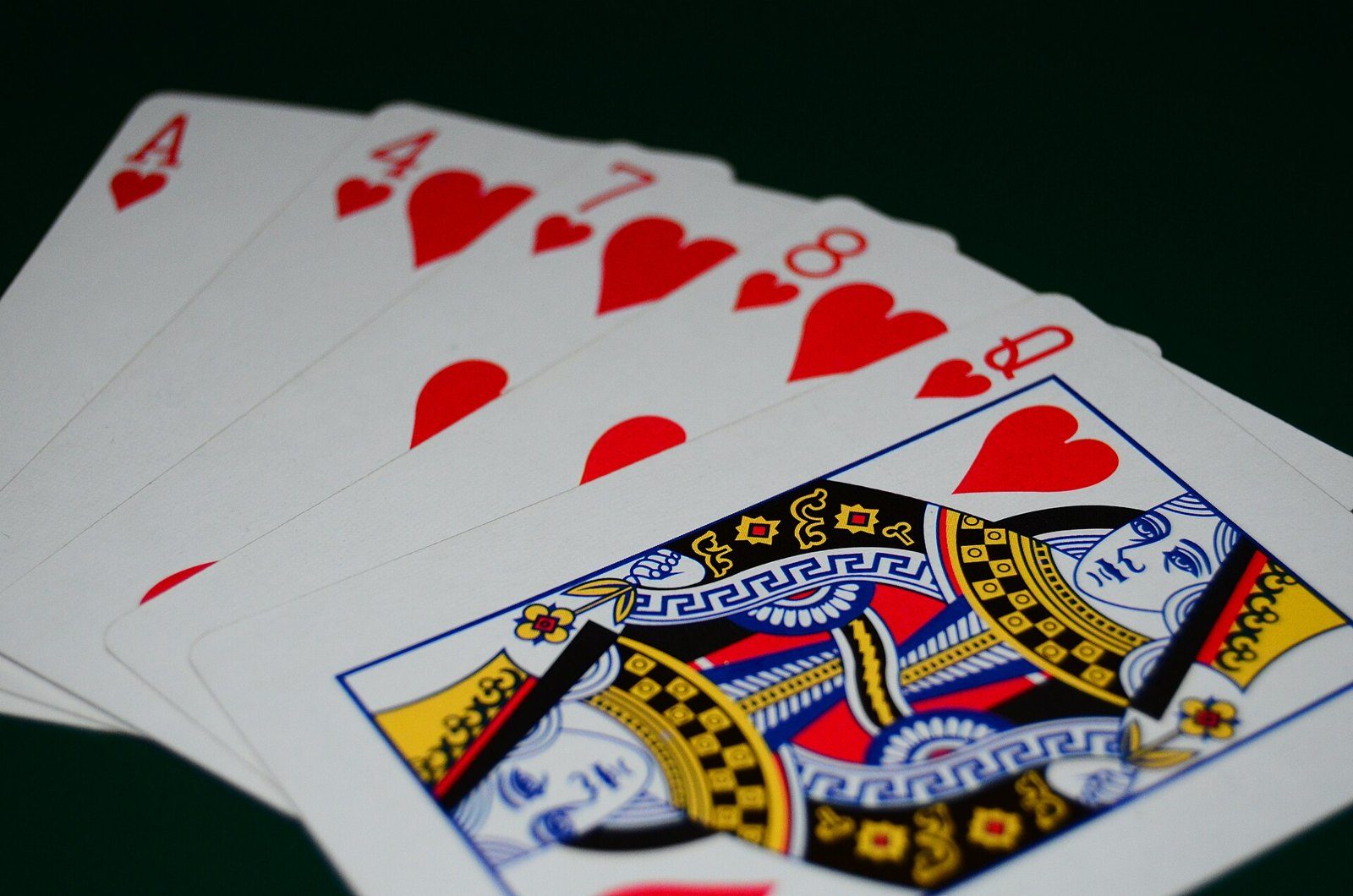 Primer plano de cinco cartas de corazones en abanico: as, 4, 7, 8 y reina, con la reina de corazones al frente