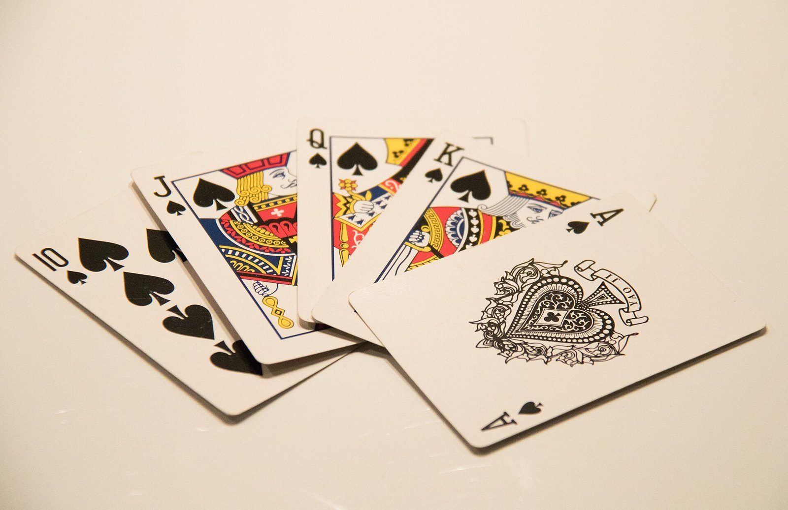 Escalera real de picas, del 10 al as, con las cartas desplegadas sobre una superficie clara