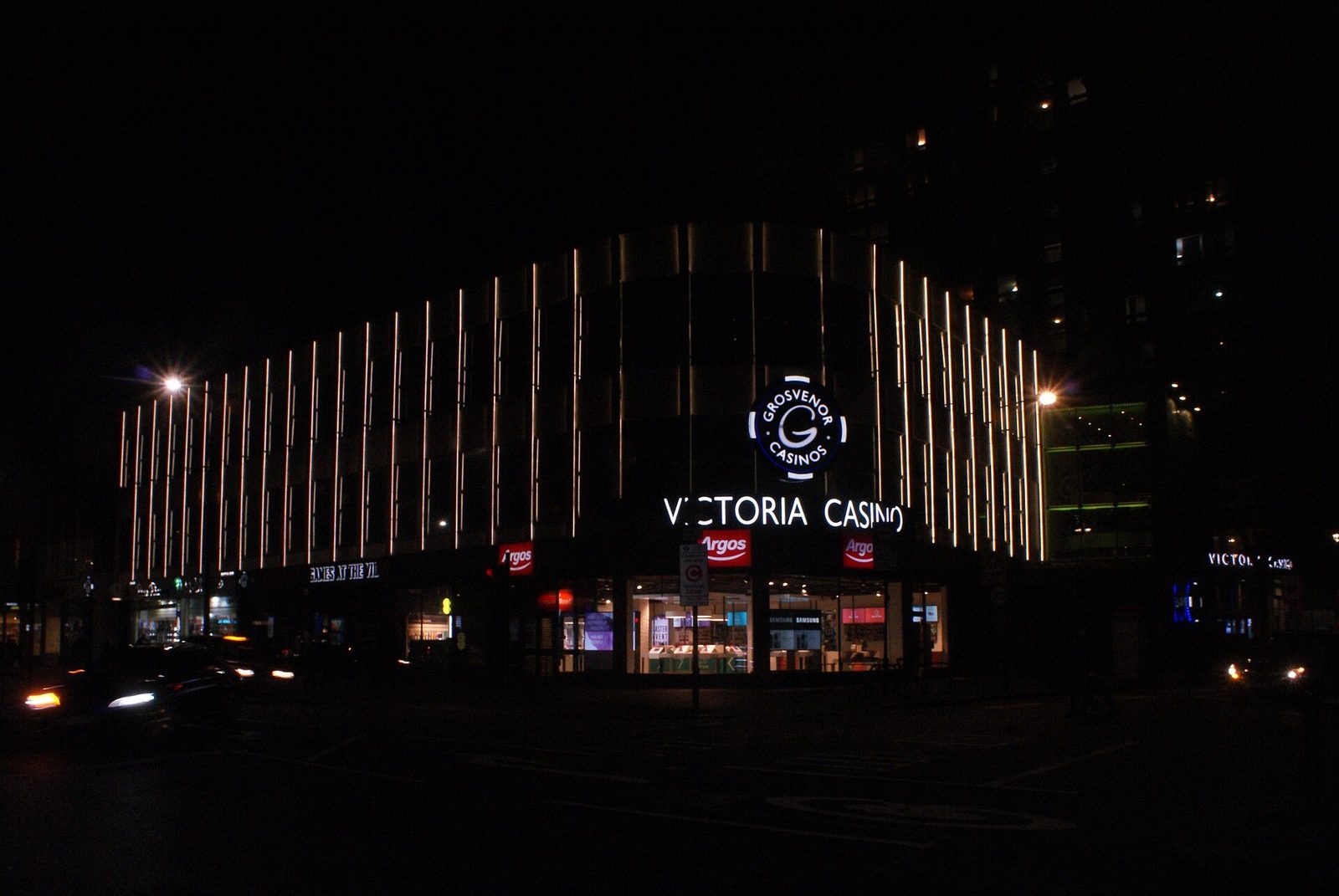 Fachada iluminada de noche del Grosvenor Victoria Casino, en Edgware Road, Londres